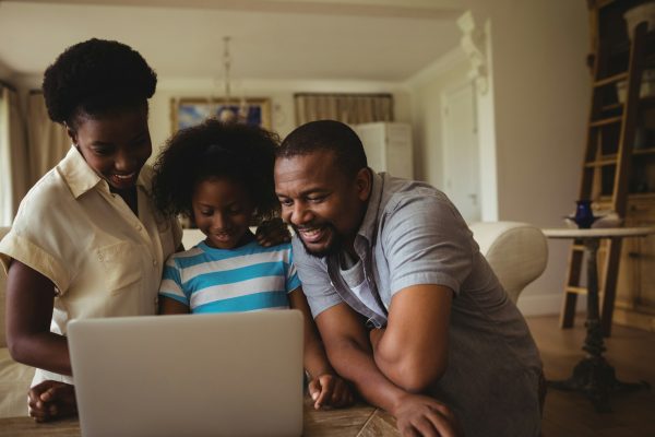 Parents and daughter using laptop in living room
